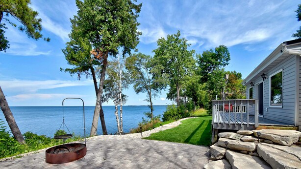 A patio with a fire pit, a stone wall, and a view of the sea.