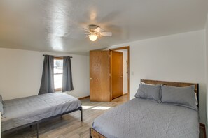 A bedroom with two single beds, a ceiling fan, and a wooden wardrobe. - Lovely Bayfront Vacation Rental w/ Spacious Deck! (Sturgeon Bay)