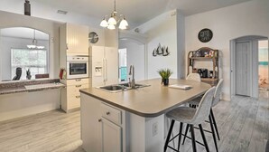 Een moderne keuken met een centraal eiland, roestvrijstalen apparatuur en een koffiebar.