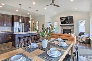 A modern kitchen with dark wood cabinets, a stainless steel refrigerator, and a dining area with a wooden table set for four. - Eden Home w/ Stunning View ~ 6 Mi to Skiing! (Eden)