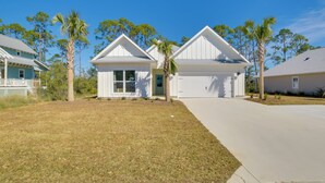 A residential area with two white houses, each with a garage and surrounded by palm trees. - Modern Port St Joe Getaway - Steps to Beach! (Port St. Joe)