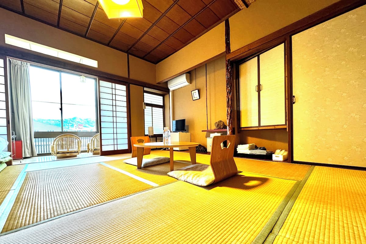 A traditional Japanese room with tatami flooring, a low table, a wooden chair, and sliding doors.