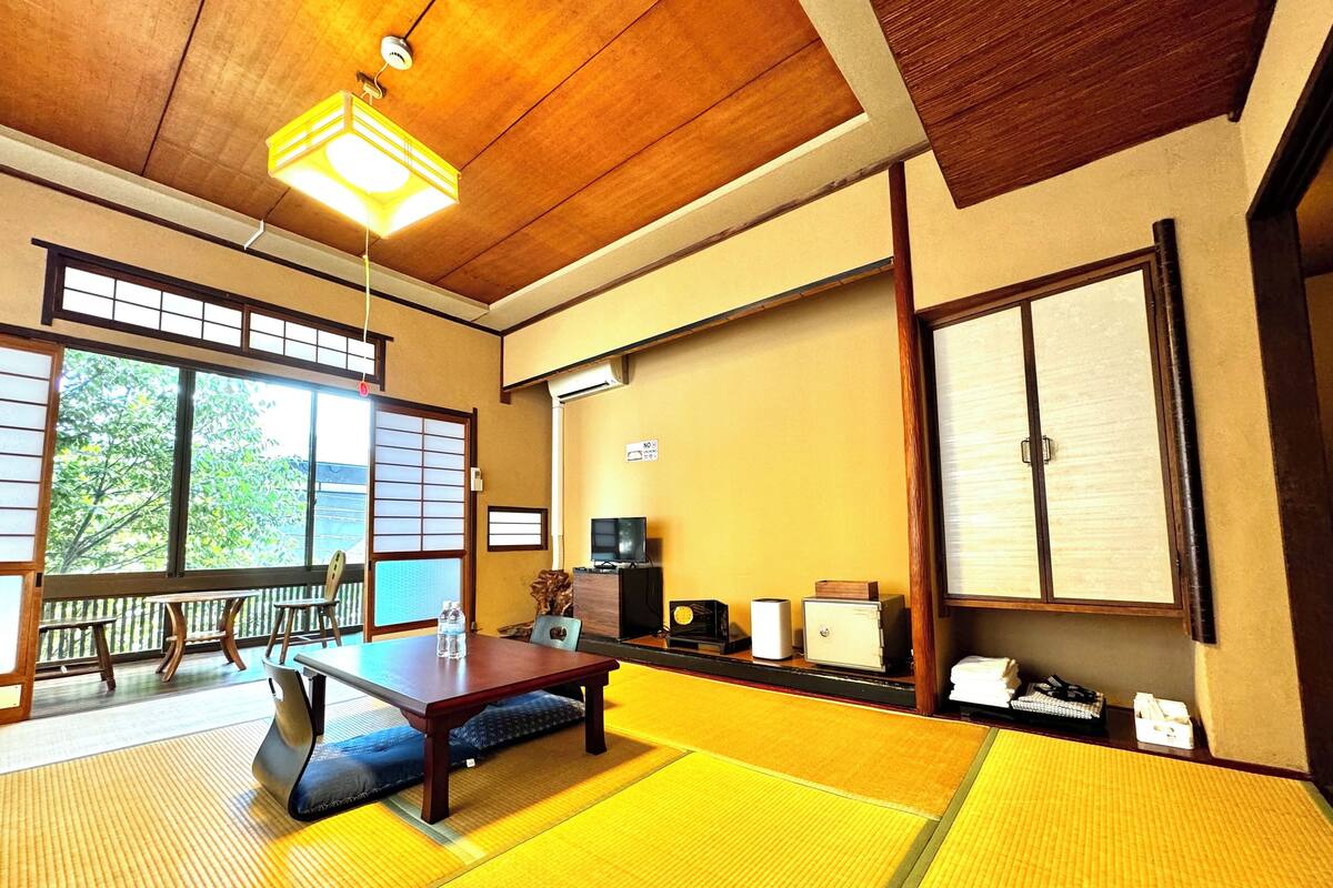 A traditional tatami mat room with a wooden table, a television, and a sliding door.