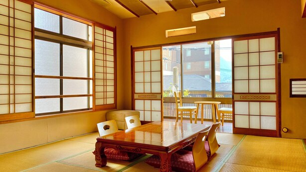 Una habitación japonesa tradicional con suelo de tatami, una mesa de madera baja y puertas correderas shoji.