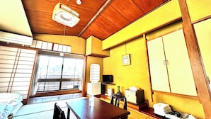 Una habitación japonesa tradicional con suelo de tatami, techo de madera y una puerta corrediza que da a un balcón.