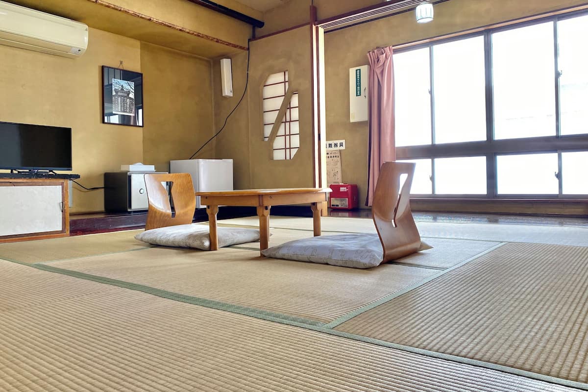 A tatami mat room with a television, a small table, and a chair.