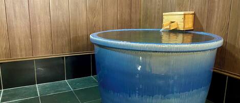 A blue water feature with a wooden structure on top, set against a wooden wall and tiled floor.