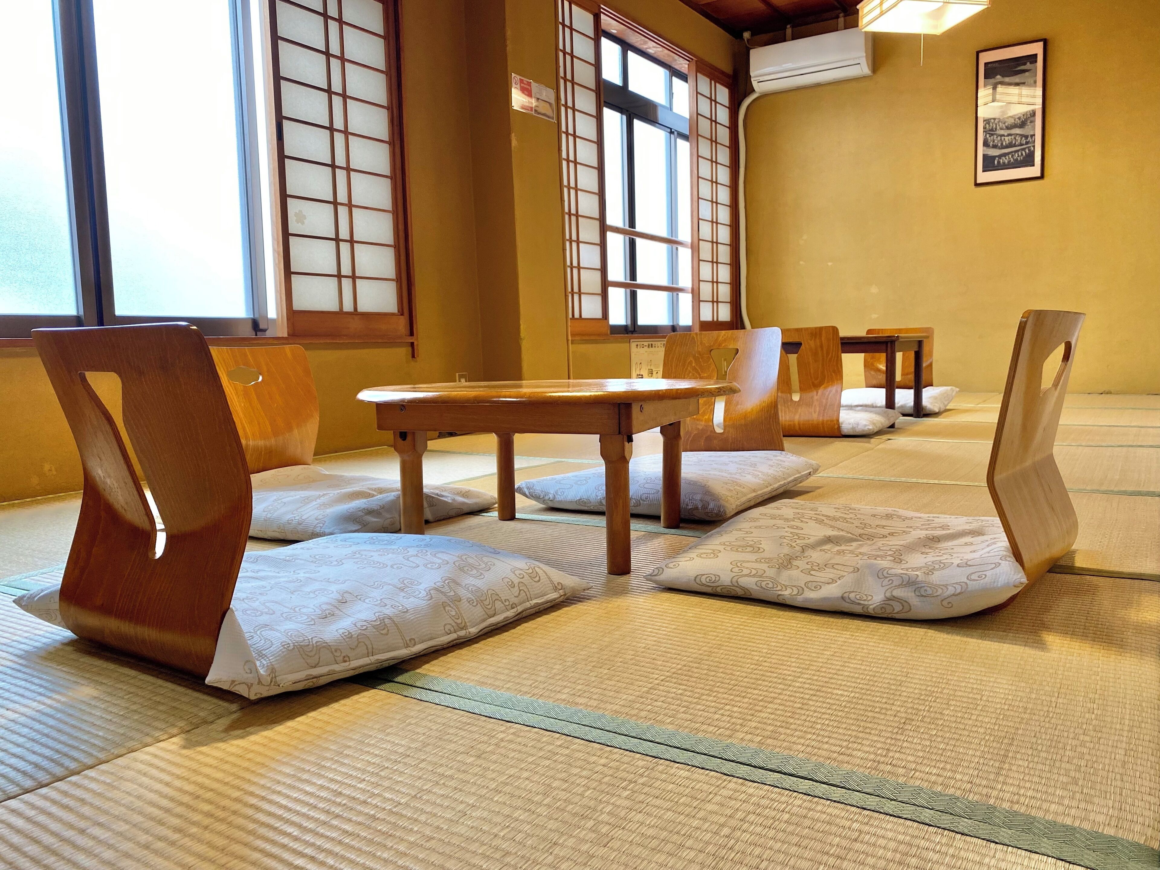 Pavimento de esteras de tatami, muebles de madera y puertas correderas shoji en una habitación tradicional.