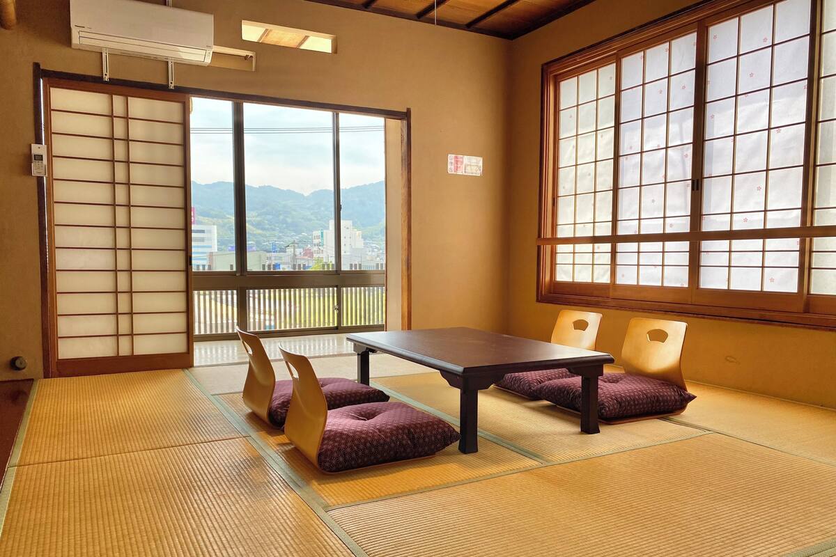 A traditional Japanese room with tatami flooring, a low table, and two cushions.