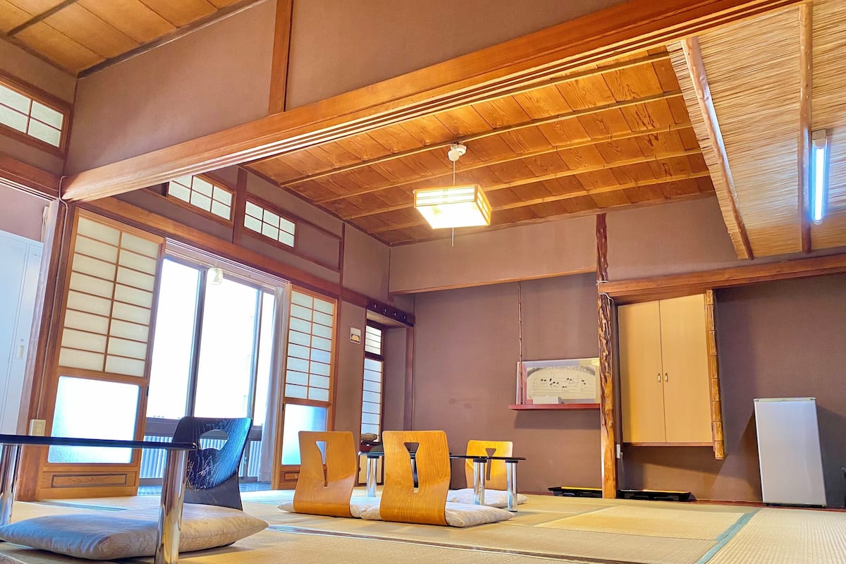 A tatami mat room with wooden beams, sliding doors, and a traditional Japanese aesthetic.