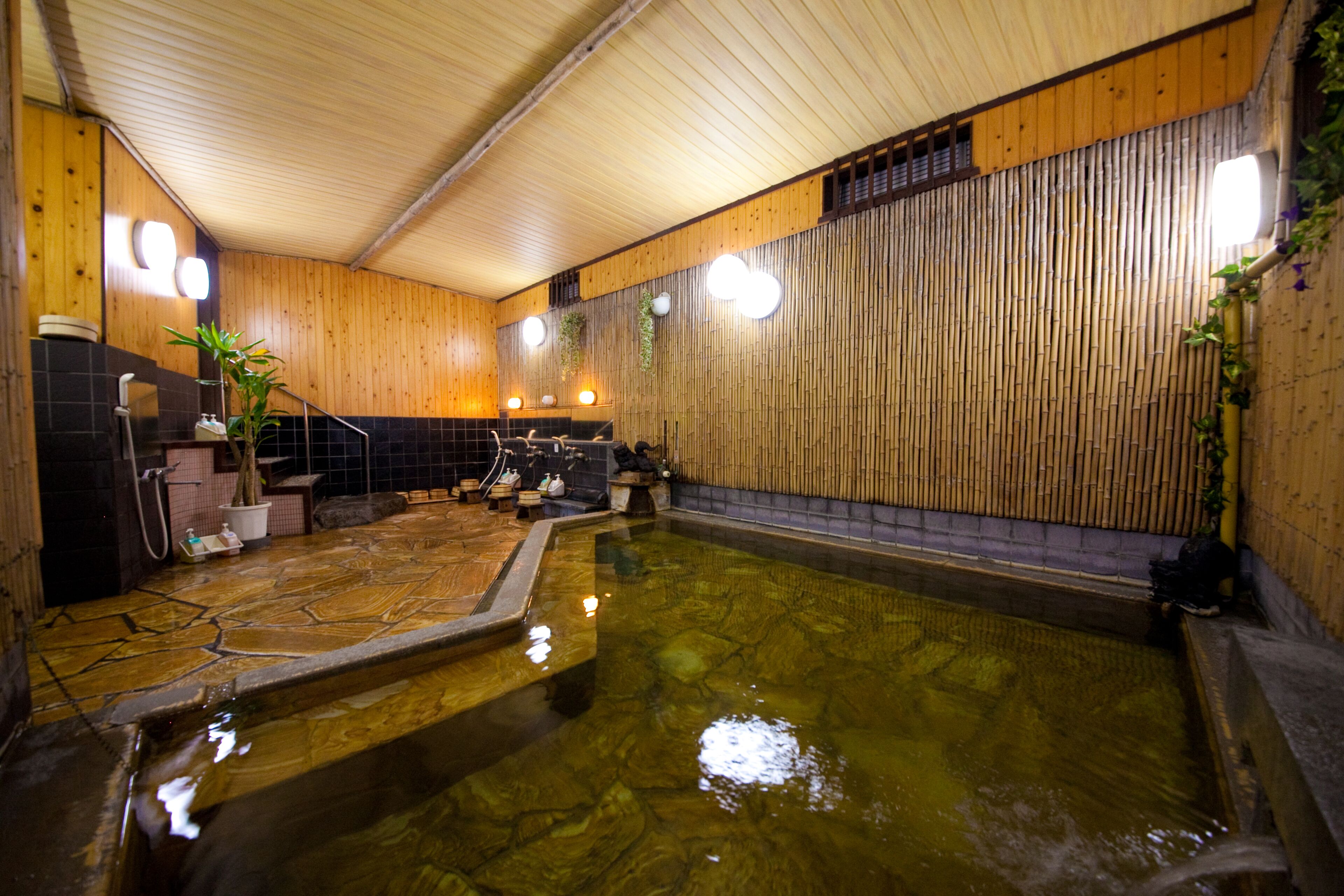 A traditional Japanese onsen with a wooden interior, a hot spring bath, and a small seating area.