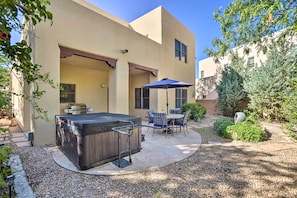 A patio area with a hot tub, outdoor furniture, and a barbecue grill.