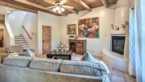Una sala de estar con chimenea, escalera y ventilador de techo.
