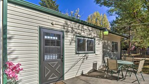 A single-story house with a green door and windows, a patio with a table and chairs, and a potted plant.
