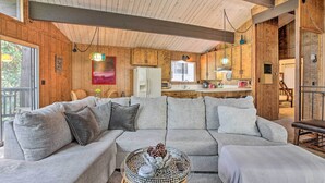 A cozy living room with a sectional sofa, a round coffee table, and wooden walls. - Lake Arrowhead Cabin w/ Mid-century Charm! (Lake Arrowhead)