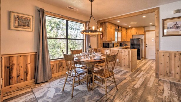 A cozy kitchen with wooden cabinets, a dining table set for four, and a large window providing natural light. - Fredricksburg Vacation Rental at 'the Loft'! (Fredericksburg)