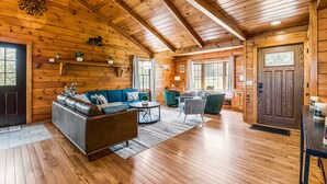 Ein Holzblockhaus-Interieur mit einer Couch, Sesseln und einem Esstisch.