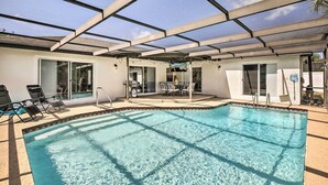 An indoor swimming pool with clear water, surrounded by a covered patio area with chairs and a table. - Lavish Holiday Home w/ Lanai & Heated Outdoor Pool (Holiday)