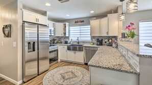 A modern kitchen with stainless steel appliances, white cabinetry, granite countertops, and a decorative rug. - Lavish Holiday Home w/ Lanai & Heated Outdoor Pool (Holiday)