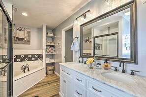 A modern bathroom with a large mirror, a bathtub, and a vanity with drawers.