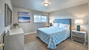 A bedroom with a bed, bedside tables, a nightstand, a window, a painting, and a ceiling light. - Apartment w/ Gas Fireplace ~ 1/2 Mi to Beach! (Anacortes)