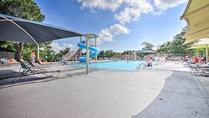 Ein Poolbereich mit Liegestühlen, einer Wasserrutsche und einer überdachten Sitzgelegenheit.