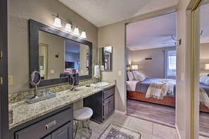 Une salle de bain dotée d’un comptoir en granit, d’un double lavabo et d’un grand miroir.