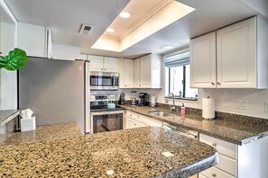 Eine moderne Küche mit Granit Arbeitsplatten, Edelstahlgeräten und weißen Schränken.
