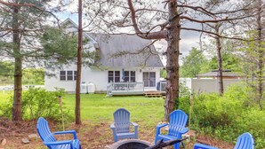 Un jardin avec un foyer et des chaises Adirondack bleues.