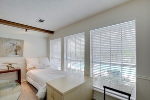 A bedroom with a bed, a nightstand, a dresser, and large windows with blinds. - Studio w/ Pool - 13 Mi to Downtown Dallas! (Dallas)