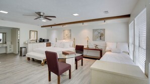 A modern bedroom with a bed, a glass table, two chairs, a ceiling fan, and a bedside table. - Studio w/ Pool - 13 Mi to Downtown Dallas! (Dallas)