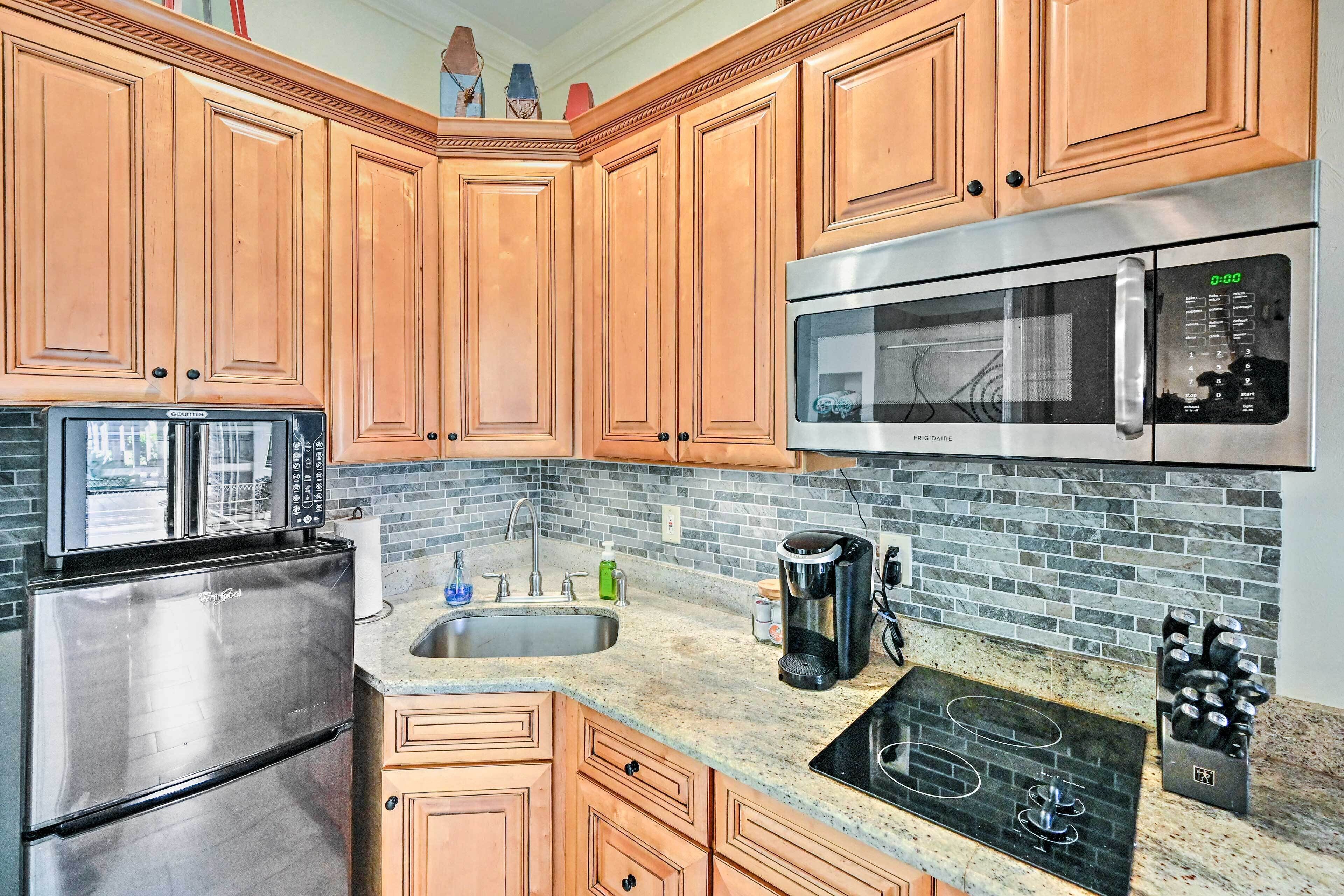 A kitchen with wooden cabinets, a stainless steel refrigerator, a microwave, a sink, and a coffee maker.