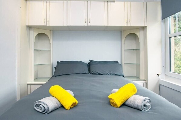 Habitación de hotel moderna con una cama grande, dos mesitas de noche y estanterías empotradas sobre la cama.