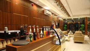 Un hall d’hôtel comprenant un comptoir d’accueil, une machine à café et une vitrine.