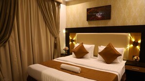 Une chambre d’hôtel avec un grand lit, une tête de lit dotée de lampes et un tableau au mur.