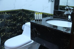 A bathroom with a white toilet, black marble sink, and a mirror above the sink. - Golden Rest Serviced Apartments (Al Khobar)