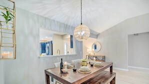 A dining area with a wooden table set for four, a hanging crystal chandelier, and a view into the kitchen. - Sunny Home w/ Golf Cart in The Villages! (The Villages)