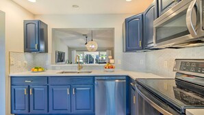 A modern kitchen with dark blue cabinets, stainless steel appliances, and a large island with a sink. - Sunny Home w/ Golf Cart in The Villages! (The Villages)