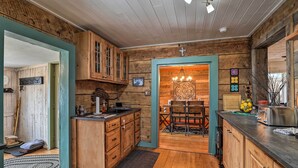 A rustic kitchen with wooden cabinets, a dining area with a table and chairs, and a chandelier. - Colorado Mountain Cabin Near National Forest! (Guffey)