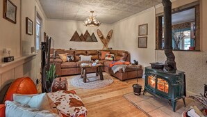 A cozy living room with a fireplace, wooden flooring, and a sectional sofa. - Colorado Mountain Cabin Near National Forest! (Guffey)