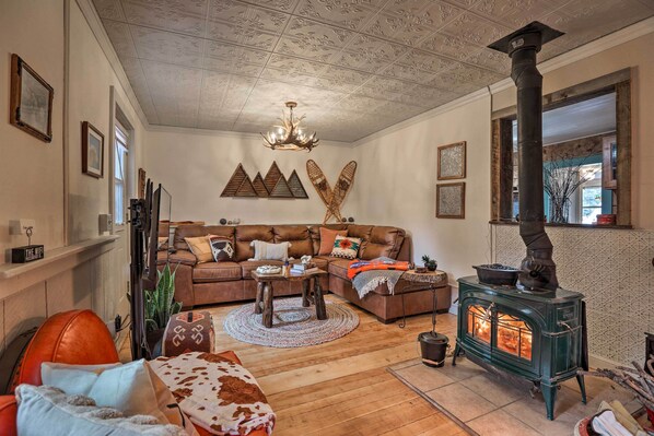A cozy living room with a fireplace, wooden flooring, and a sectional sofa. - Colorado Mountain Cabin Near National Forest! (Guffey)