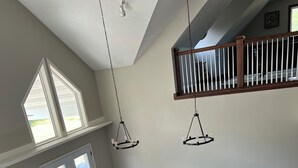 A spacious living room with a large sectional sofa, a dining area with a wooden table and chairs, and a staircase with a railing. - An Oasis on the Lake (New London)