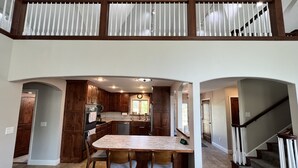 A spacious kitchen with a central island, wooden cabinets, and a dining area with two chairs. - An Oasis on the Lake (New London)