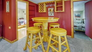 A room with a wooden table and four stools, red walls, and a door leading to another room. - Grand Lake Waterfront Home: 2 Boat Docks (Grove)