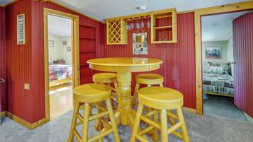 A room with a wooden table and four stools, red walls, and a door leading to another room.