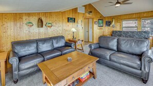 A cozy living room with two leather sofas, a wooden coffee table, and a ceiling fan. - Grand Lake Waterfront Home: 2 Boat Docks (Grove)