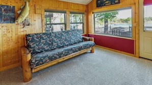 A wooden interior with a sofa, a fish mounted on the wall, and a view of the outside. - Grand Lake Waterfront Home: 2 Boat Docks (Grove)