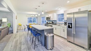 A modern kitchen with white cabinets, stainless steel appliances, a central island with bar stools, and a trash can. - 3 Mi to Kalahari: Pocono Summit Home w/ Game Room! (Pocono Summit)