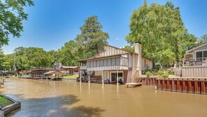 A lakeside cabin with a dock, surrounded by trees and a clear sky. - Spacious Deck: Waterfront Home in Gun Barrel City! (Mabank)