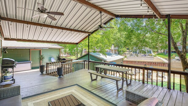 A covered outdoor deck with a ceiling fan, picnic table, and seating area. - Spacious Deck: Waterfront Home in Gun Barrel City! (Mabank)